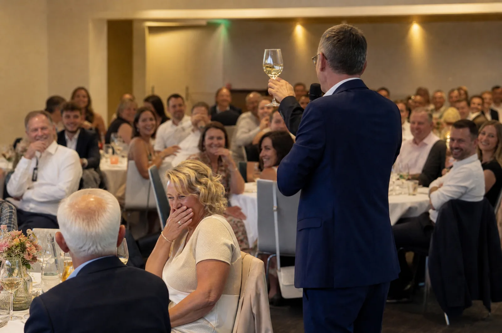 Fünfzigster Geburtstag im gemieteten Saal, ein Gast hält eine Rede, Gläser erhoben
