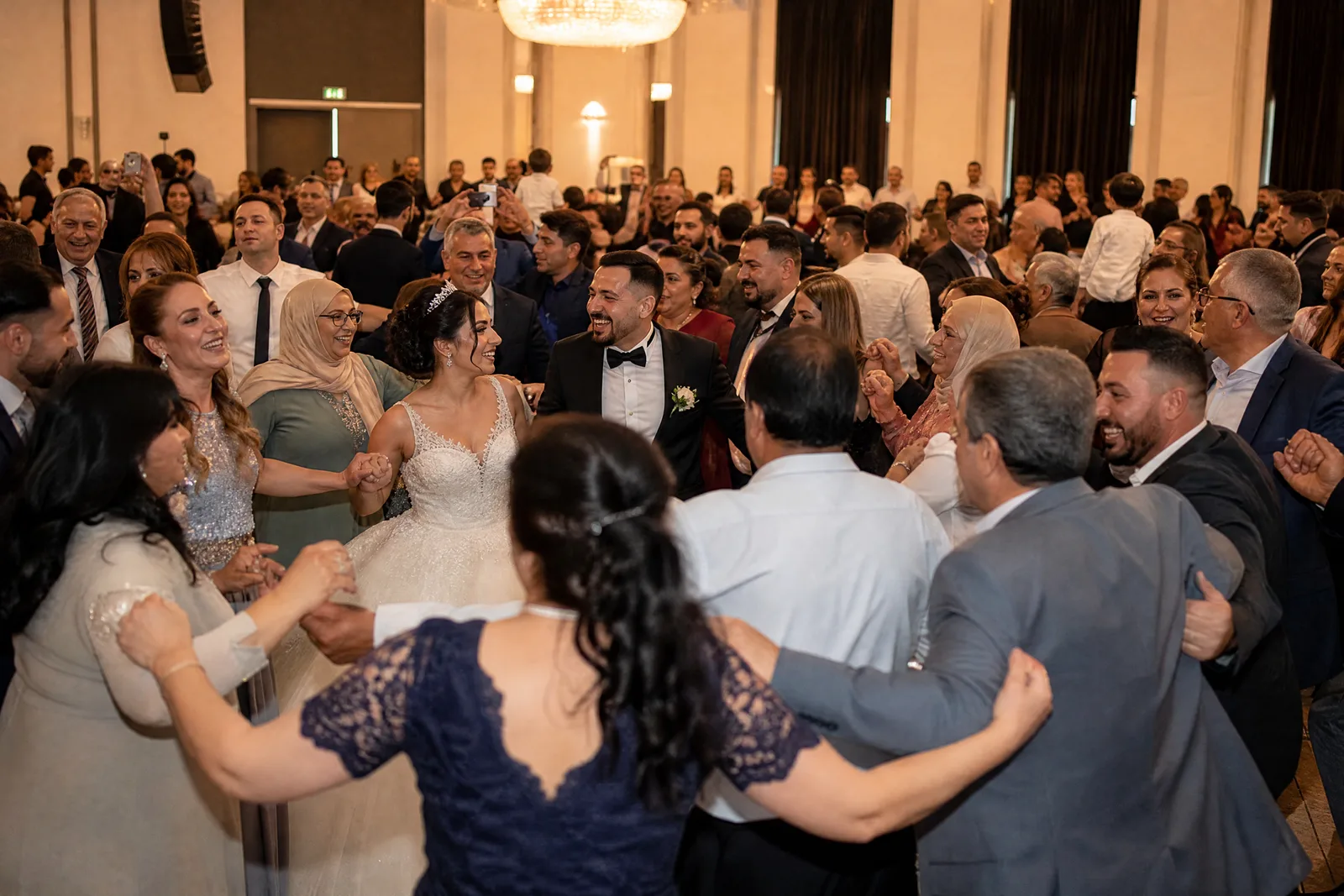 Gäste tanzen bei einer türkisch-deutschen Hochzeit im Kreis, das Brautpaar in ihrer Mitte