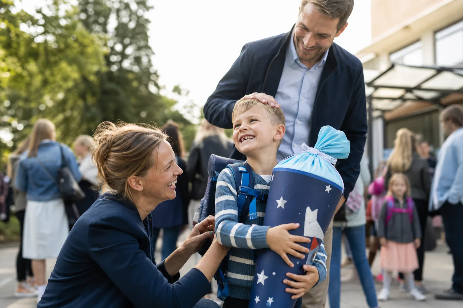 Ein Junge mit Schultüte am ersten Schultag, die Mutter richtet ihm den Ranzen, der Vater steht dahinter