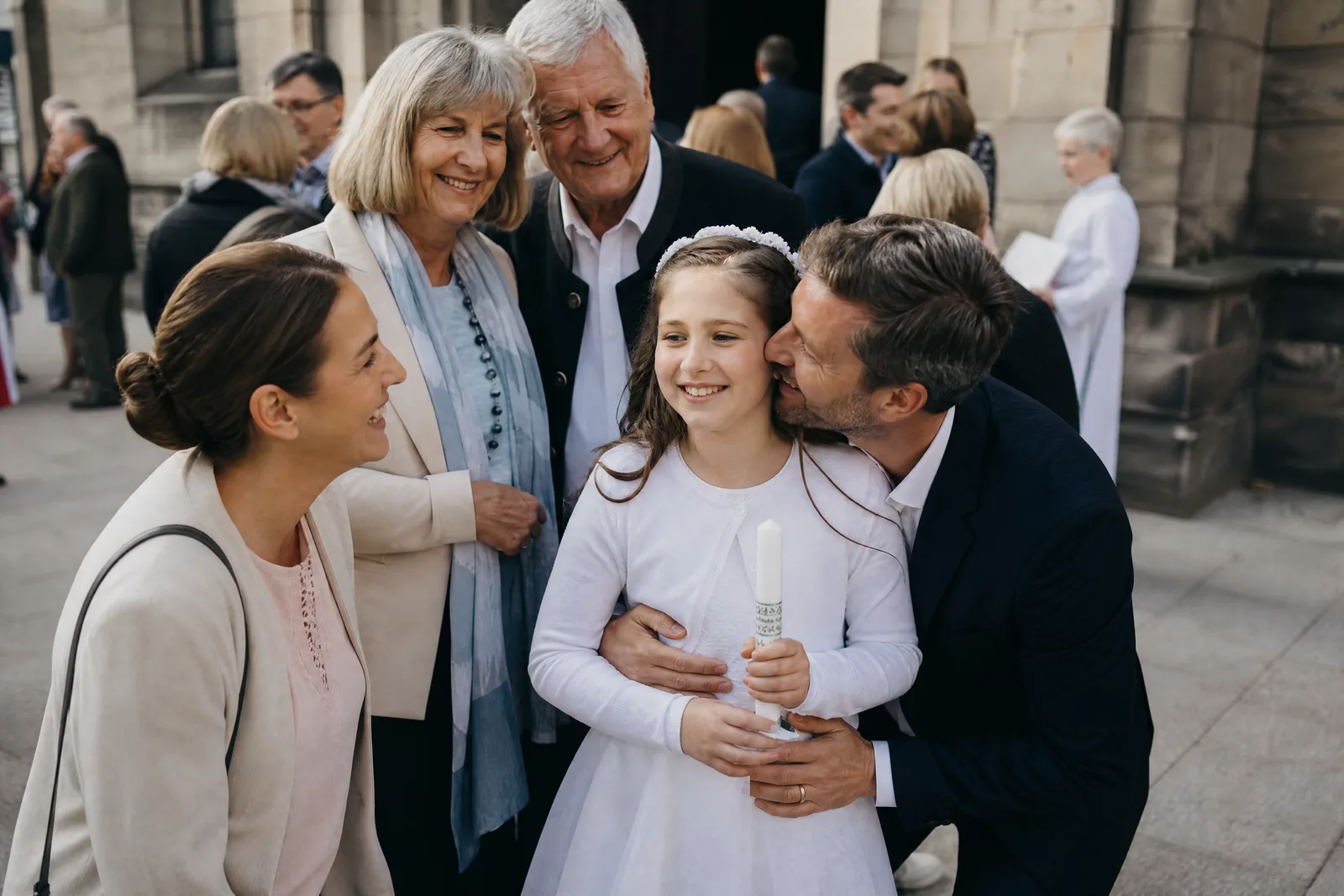 Ein Mädchen im weissen Kleid wird nach der Erstkommunion von seinem Vater umarmt