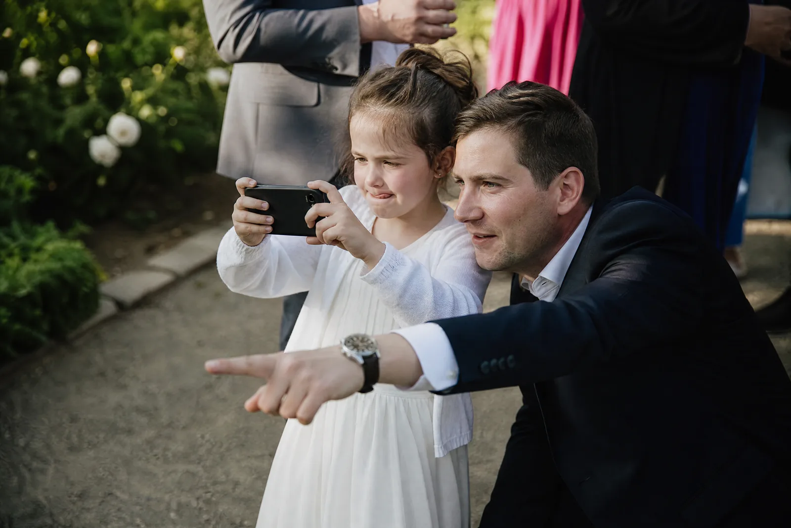 Ein Kind hält konzentriert ein Handy mit beiden Händen, ein Erwachsener zeigt daneben